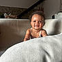 Mïa participe au concours pour gagner de l'argent avec cette photo : baby, child, smiling, curly_hair, couch, indoor, cozy, skin, face, person, furniture, staircase, stone_wall, tank_top, happy, infant, portrait, reaching, living_room, natural_light