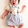 baby, infant, yawning, cute_outfit, suspenders, bow_tie, white_shirt, shorts, lying_down, textured_blanket, sleepy, hair, spiky_hair, skin, newborn, child, indoors, portrait, adorable, soft_lighting