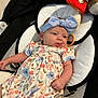 Remi is registered to the contest to win money with this photo: baby, headband, blue, bow, floral_dress, cushion, baby_seat, plush_toys, comfort, infant, cute, child, relaxing, indoor, soft, patterned_clothing, colorful, small_child, adorable, person