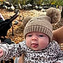 baby, child, hat, pom_poms, knitwear, outdoor, fall, leaves, stroller, hand, cute, tongue_out, person, face, cheeks, clothing, pattern, animal_print, nature, daylight