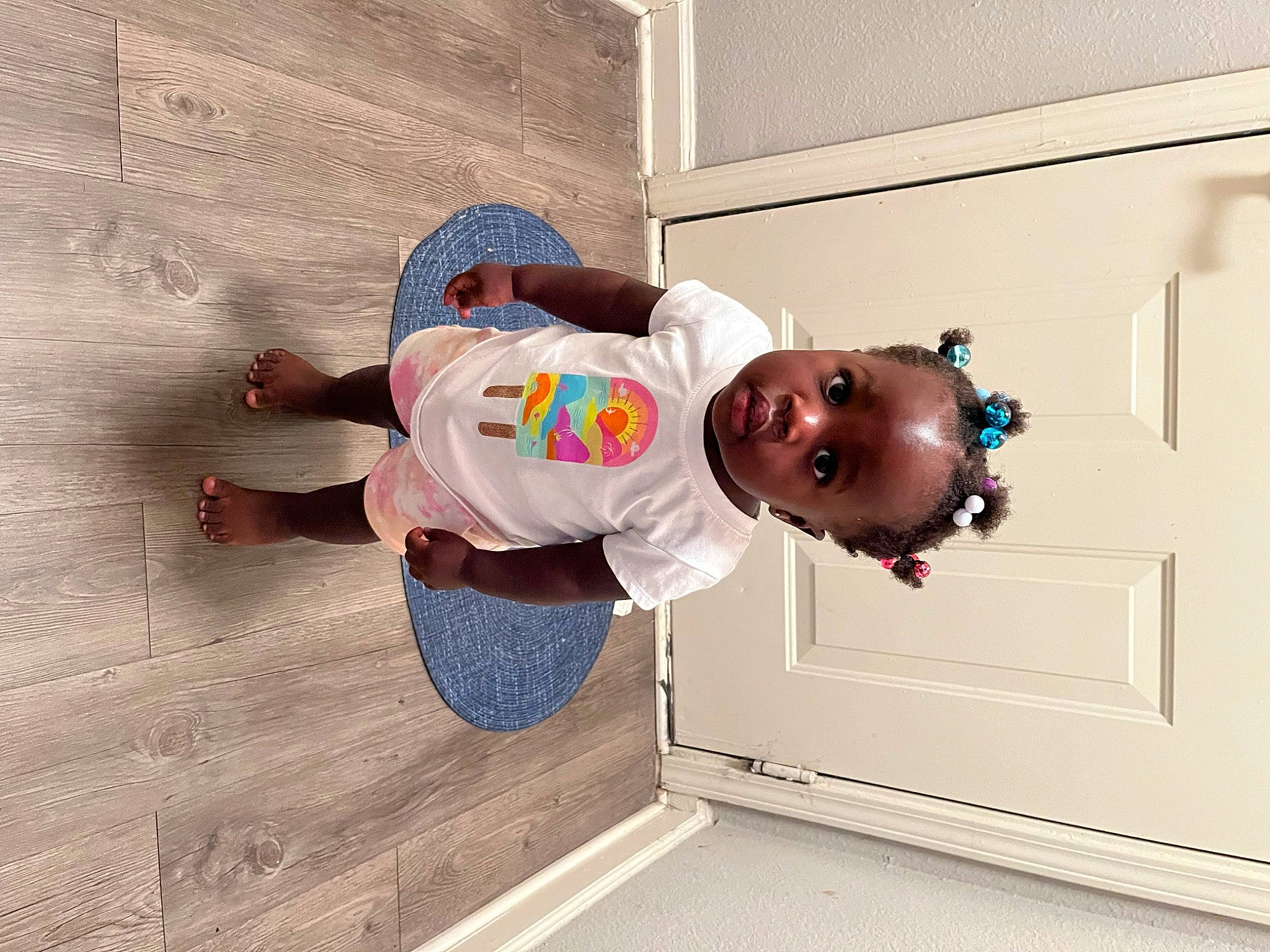 Nova is registered to the contest to win money with this photo: baby, baby_toddler_clothing, child, door, flooring, fun, happy, hardwood, hat, person, room, sleeve, smile, t_shirt, toddler, wood