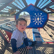 Kendrick joined the competition — help win amazing prizes! child, toddler, playground, outdoor, sunlight, metal_structure, patterned_shadows, blue_sky, casual_clothing, sitting, curious, young_child, play_equipment, daylight, recreation, park, expression, head, face, hands