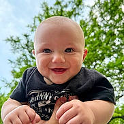 Isaiah is registered to the contest to win money with this photo: baby, child, smiling, happy, face, hands, outdoor, nature, greenery, sky, portrait, cute, infant, person, toddler, holding, black_shirt, daylight, closeup, joyful