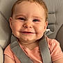 baby, car_seat, child, chubby_cheeks, close_up, cute, face, hand, happy, indoor, infant, peach_shirt, person, portrait, seat, seat_belt, skin, smiling, straps, young
