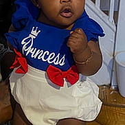 Faith is registered to the contest to win money with this photo: baby, child, infant, girl, red_bow, headband, blue_top, white_shorts, shoes, bracelet, standing, indoors, wooden_floor, staircase, person_holding, cute, expression, clothing, fashion, portrait