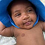 baby, infant, blue_hat, smile, tongue_out, dimples, close_up, skin, cute, child, outdoor, blanket, sun_hat, happy, face, portrait, headwear, young, relaxing, person