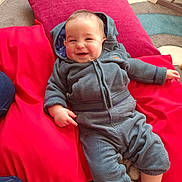 Lucas a rejoint le concours — aidez-le/la à gagner de superbes lots ! baby, child, smiling, hoodie, pants, cushions, red, blue, carpet, indoor, happy, infant, cute, cozy, relaxing, person, casual_clothing, floor, playful, home