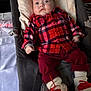 baby, infant, plaid_shirt, red_clothing, baby_chair, pillow, white_socks, red_heart, indoor, face, person, cute, cozy, plush, clothing, child, portrait, expression, seated, holiday