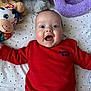 baby, child, smiling, red_sweater, stuffed_animals, soft_toys, polka_dot_sheet, happy, indoor, portrait, cute, infant, lying_down, face, blue_eyes, clothing, home, playful, young_child, cozy