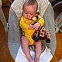 baby, barefoot, bouncer_seat, child, cozy, cute, hands, head, indoors, infant, leg, plush_giraffe, polka_dots, portrait, relaxed, seat_buckle, soft_toy, toy, wooden_floor, yellow_onesie