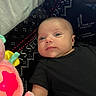 baby, infant, black_clothing, plush_toy, pink, star, blanket, pattern, face, person, indoor, soft_toy, cute, child, young, resting, lying_down, expression, cozy, colorful