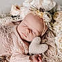 baby, sleeping, flower_headband, pink_lace, knitted_heart, fluffy_rug, cream_flowers, newborn, portrait, soft_lighting, peaceful, cute, infant, wrapped, closeup, tender, resting, cozy, delicate, adorable