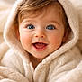 baby, infant, blue_eyes, smile, hood, blanket, knitted, cozy, portrait, closeup, chubby_cheeks, joyful, soft_texture, adorable, mouth_open, long_eyelashes, brown_hair, warm_tones, neutral_background, clothing