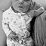 baby, newborn, sleeping, onesie, knitted_socks, infant, hand, face, cute, resting, soft, cozy, patterned_clothing, portrait, black_and_white, peaceful, closeup, person, child, indoors
