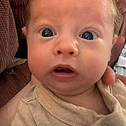 Forrest is registered to the contest to win money with this photo: baby, infant, face, wide_eyes, expression, beige_clothing, hand, supporting, closeup, portrait, indoor, couch, fabric, texture, skin, newborn, person, young_child, cute, surprised