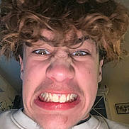 Kasey participe au concours pour gagner de l'argent avec cette photo : person, face, curly_hair, expression, grimace, teeth, indoor, sweatshirt, young_person, closeup, casual, head, skin, mouth, nostrils, hair, emotion, portrait, selfie, human