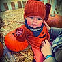 baby, child, pumpkin, hay, orange_clothing, knit_hat, halloween, bib, autumn, seasonal, cute, hand, person, outdoor, smiling, face, festive, holiday, warm_clothing, young_child