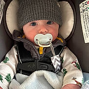 Everett is registered to the contest to win money with this photo: baby, infant, pacifier, car_seat, hat, knit_hat, bear_ears, blanket, clothing, safety_harness, wide_eyes, cute, child, indoors, portrait, winter_clothing, holiday_theme, soft_texture, close_up, warm