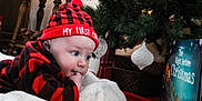 Everett is registered to the contest to win money with this photo: baby, child, christmas, holiday, hat, plaid, red, black, blanket, book, ornament, christmas_tree, decorations, indoor, cute, face, person, festive, winter, cozy