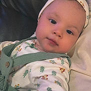 Ayla joined the competition — help win amazing prizes! baby, infant, headband, green_clothing, floral_pattern, couch, leather, portrait, child, young_child, face, eyes, indoor, person, cute, comfortable, relaxed, soft_lighting, closeup, apparel