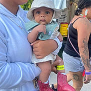 Josiah is registered to the contest to win money with this photo: baby, child, person, hat, bib, boots, cowboy_boots, holding, hoodie, tattoos, earrings, outdoor, festival, tent, walking, curious, keychain, glasses, shorts, summer