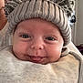 Leo is registered to the contest to win money with this photo: baby, child, hat, knit_hat, pom_poms, smile, tongue_out, face, close_up, cute, cozy, warm_clothing, infant, person, indoors, apparel, headwear, expression, happy, portrait