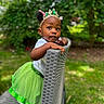 toddler, child, girl, green_tutu, crown, outdoor, garden, chair, curious, portrait, cute, fashion, headwear, nature, grass, daylight, person, smile, playful, young_child