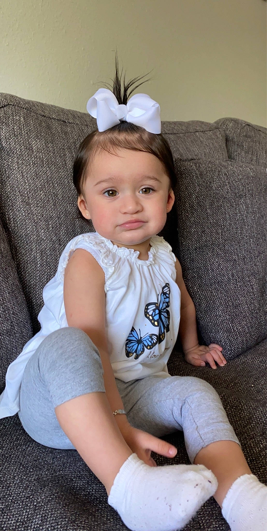 Melaina is registered to the contest to win money with this photo: active_tank, ankle, baby, baby_toddler_clothing, barefoot, child, comfort, costume_accessory, couch, foot, hair_accessory, headband, headpiece, lap, living_room, person, shoe, sitting, slipcover, sock