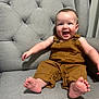 Korbin is registered to the contest to win money with this photo: armchair, baby, barefoot, brown_clothing, child, cute, face, grey_furniture, happy, human, indoors, infant, joyful, overalls, person, portrait, sitting, smiling, toddler, young_child