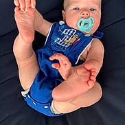 Korbin is registered to the contest to win money with this photo: baby, blue_clothing, child, closeup, comfort, cushion, cute, fabric, face, feet, hand, indoor, infant, pacifier, person, playful, portrait, relaxing, romper, skin