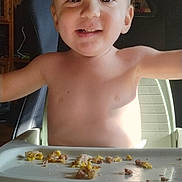 Tucker is registered to the contest to win money with this photo: toddler, child, high_chair, smile, food, messy, indoor, baby, feeding, happy, face, human, seat, chicco, young_child, eating, kitchen, light, person, mealtime