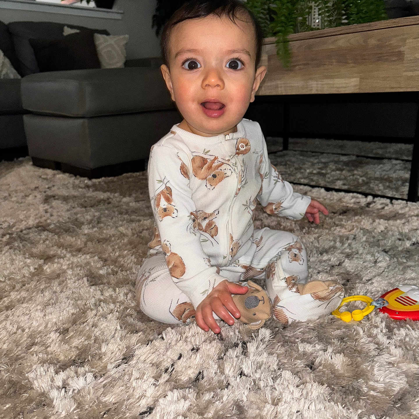Zayne joined the competition — help win amazing prizes! baby, carpet, child, couch, cozy, curious, cute, floor, furniture, home, indoor, infant, living_room, pajamas, person, plant, plush_toy, sitting, soft_lighting, wide_eyes