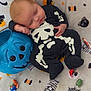 Jaxon is registered to the contest to win money with this photo: baby, sleeping, onesie, skeleton_costume, halloween, pumpkin_bucket, blue_pumpkin, candy, blanket, spooky, cute, infant, child, costume, holiday, festive, resting, black_clothing, pattern, soft_toys
