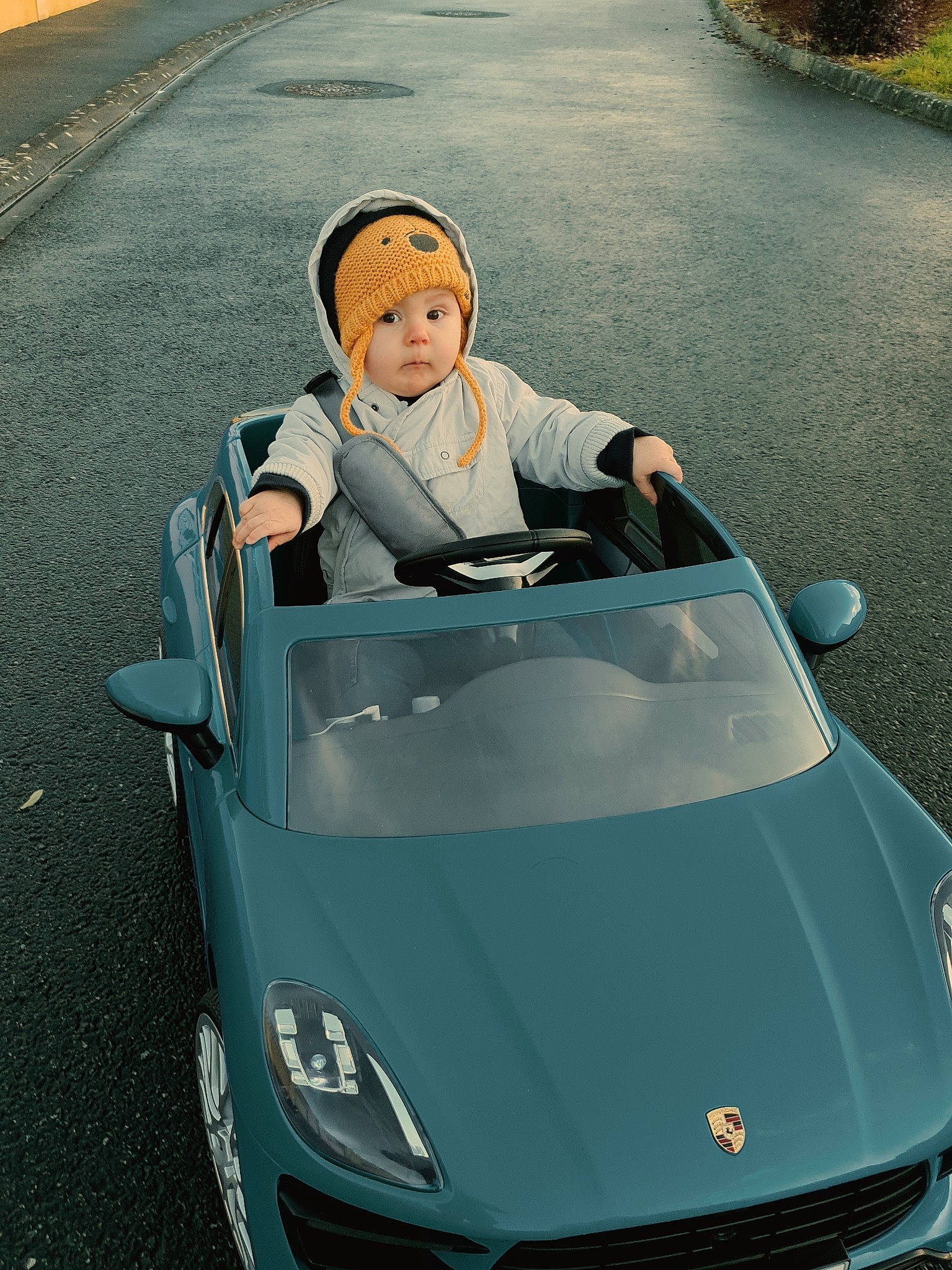 Jullian a rejoint le concours — aidez-le/la à gagner de superbes lots ! asphalt, auto_part, automotive_design, automotive_exterior, automotive_lighting, automotive_mirror, automotive_window_part, bumper, driving, fender, glass, grille, headlamp, headwear, hood, mode_of_transport, motor_vehicle, person, toddler, vehicle