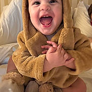 Justin is registered to the contest to win money with this photo: baby, child, smiling, happy, cute, costume, bear, hood, plush, soft, bed, blanket, pajamas, infant, indoors, portrait, sitting, hands, face, joy