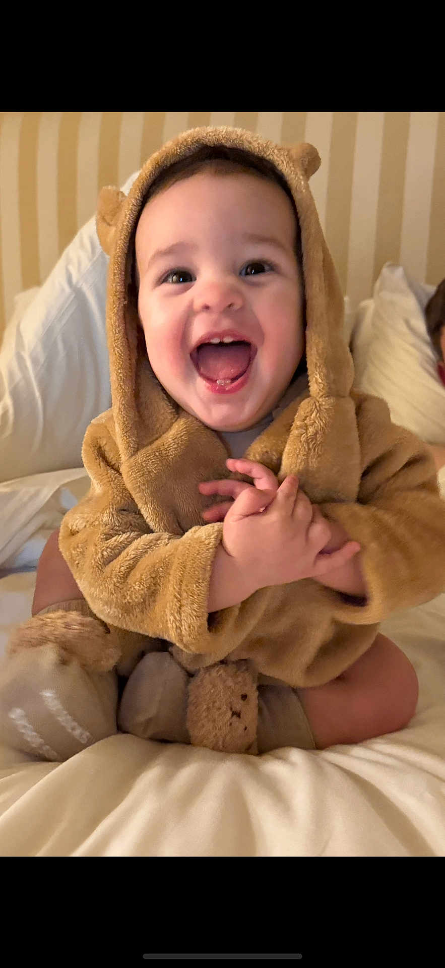 Justin is registered to the contest to win money with this photo: baby, child, smiling, happy, cute, costume, bear, hood, plush, soft, bed, blanket, pajamas, infant, indoors, portrait, sitting, hands, face, joy