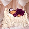 newborn, baby, sleeping, purple_dress, headband, flower, miniature_bed, lace_blanket, pastel_background, soft_lighting, portrait, infant, cute, peaceful, studio_photo, fabric, decor, tulle, baby_fashion, resting