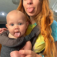 Maverick joined the competition — help win amazing prizes! baby, woman, tongue_out, baby_carrier, piercing, indoor, light_fixture, tie_dye_shirt, long_hair, orange_hair, hand_holding, playful, portrait, person, cute, happy, family, casual, blue_eyes, home