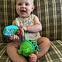 baby, child, toy, couch, plaid, smile, happy, sitting, indoor, person, infant, clothing, foot, hand, face, play, colorful, cute, expression, furniture