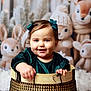 baby, toddler, child, smile, green_dress, hair_bow, basket, portrait, indoor, stuffed_animal, plush_toy, deer, rabbit, winter_decor, cozy, holiday, wooden_basket, soft_toys, cheeks, happy_face