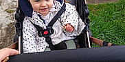 Ruby a rejoint le concours — aidez-le/la à gagner de superbes lots ! child, toddler, stroller, pram, grass, sidewalk, pavement, jacket, polka_dots, socks, seatbelt, smiling, face, hairclip, hand, wheel, concrete, outdoor, pathway, legs