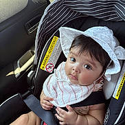 Louisa joined the competition — help win amazing prizes! baby, infant, child, car_seat, vehicle,  bonnet, bib, striped_clothing, white_clothing, sitting, reclining, face, eyes, brown_hair, looking_at_camera, indoors, travel, seatbelt, portrait, safe