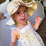 Mia a rejoint le concours — aidez-le/la à gagner de superbes lots ! child, closeup, cute, dress, expression, eyes, face, hand, happy, hat, indoor, palm_tree_print, patterned_clothing, person, skin, smiling, sofa, summer, sun_hat, toddler