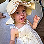child, closeup, cute, dress, expression, eyes, face, hand, happy, hat, indoor, palm_tree_print, patterned_clothing, person, skin, smiling, sofa, summer, sun_hat, toddler