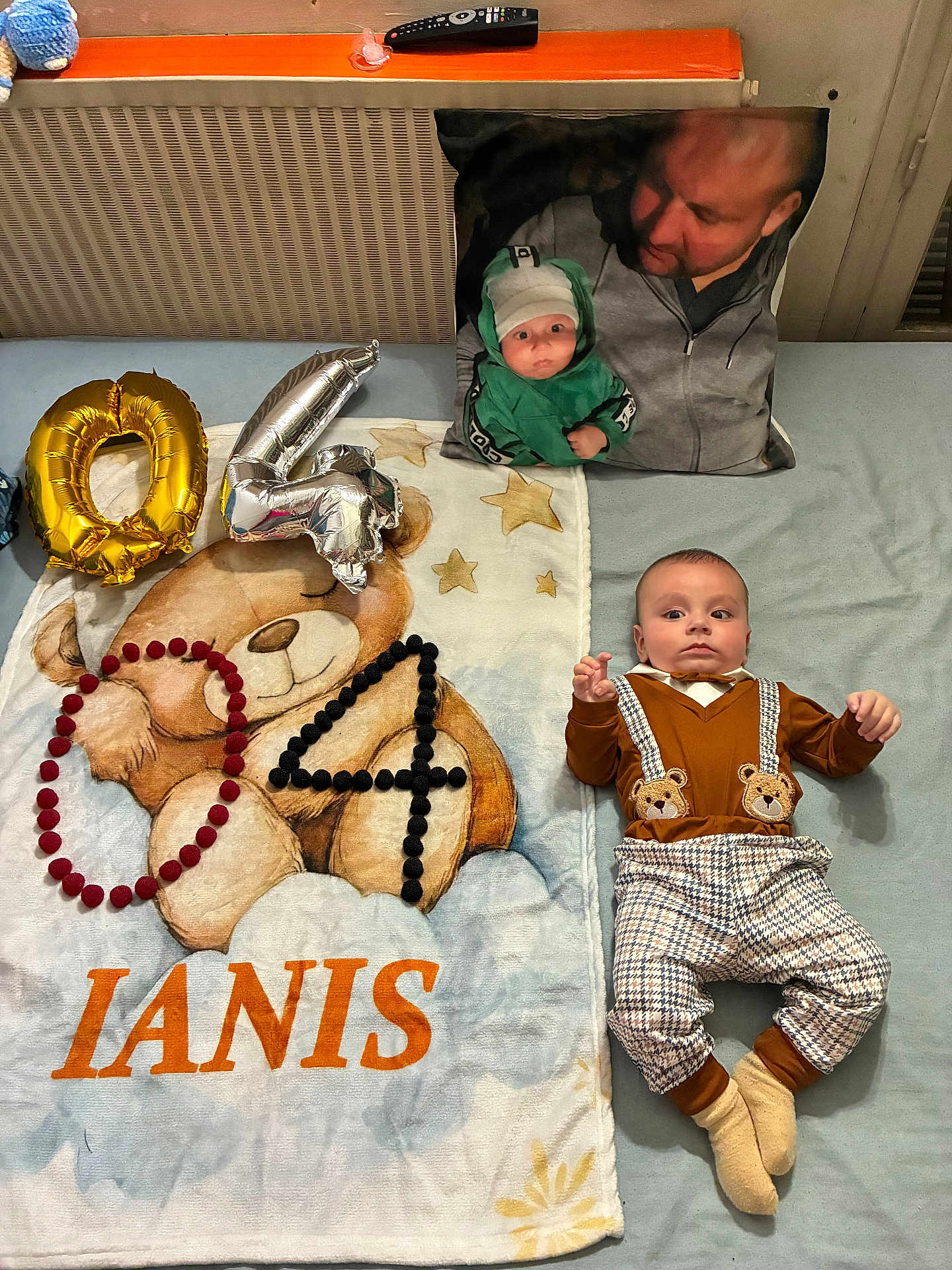 Ianis a rejoint le concours — aidez-le/la à gagner de superbes lots ! baby, blanket, balloons, pillow, teddy_bear, pom_poms, person, face, clothing, bed, stars, name, number, orange, gray, plaid, socks, indoor, cute, portrait