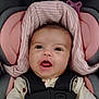 Justice is registered to the contest to win money with this photo: baby, child, car_seat, pink, cherry_pattern, clothing, face, infant, happy, smiling, safety_harness, head_support, cute, young, indoors, portrait, seatbelt, person, infant_clothing, expression