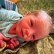 Jasper is registered to the contest to win money with this photo: newborn, baby, infant, face, eyes, hand, blanket, pattern, clothing, striped, sleepwear, skin, portrait, closeup, lying_down, young_child, cute, indoors, soft_lighting, resting