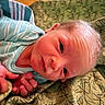 baby, blanket, closeup, clothing, cute, eyes, face, hand, indoors, infant, lying_down, newborn, pattern, portrait, resting, skin, sleepwear, soft_lighting, striped, young_child