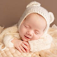 Evie is registered to the contest to win money with this photo: baby, sleeping, knitted_hat, white_clothing, soft_texture, blanket, cozy, infant, cute, peaceful, newborn, portrait, hands, closed_eyes, warm_colors, headwear, resting, toddler, studio_photo, soft_lighting