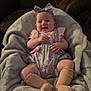 Evie joined the competition — help win amazing prizes! baby, infant, smiling, headband, romper, blanket, couch, socks, happy, child, indoors, person, seated, soft_fabric, cozy, cute, patterned_clothing, legs, arms, face